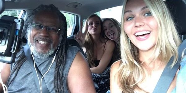 Four people smiling inside a car, enjoying a selfie moment.
